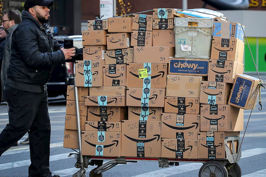 Un repartidor lleva múltiples paquetes de Amazon Prime
